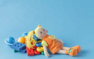 Doo laying on pile of toys with bright blue background