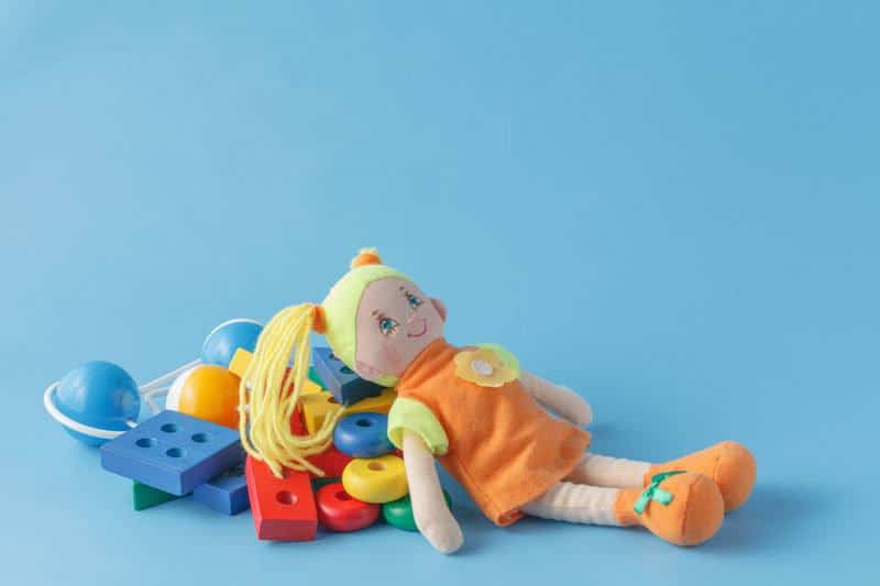 Doo laying on pile of toys with bright blue background